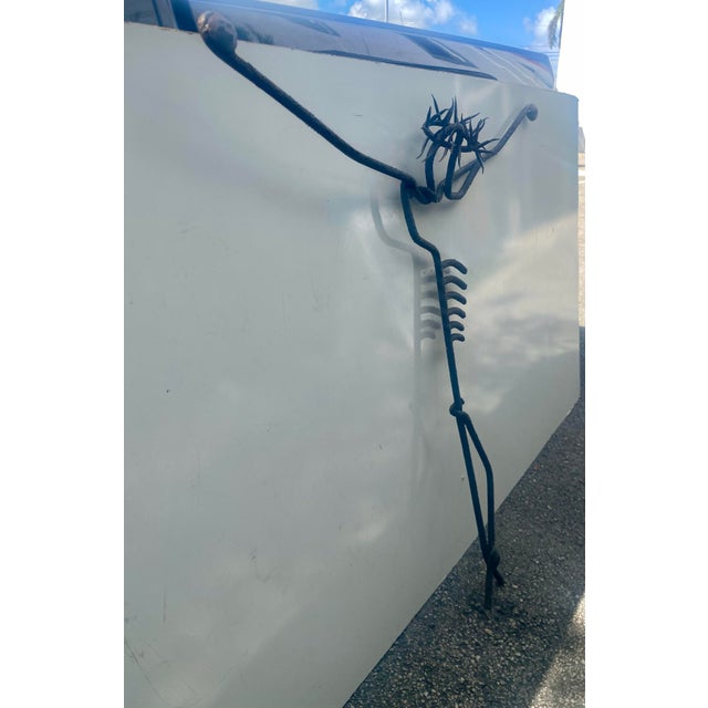 Brutalist style metal sculpture, likely depicting a stylized crucifixion figure. • It is constructed from forged iron or...