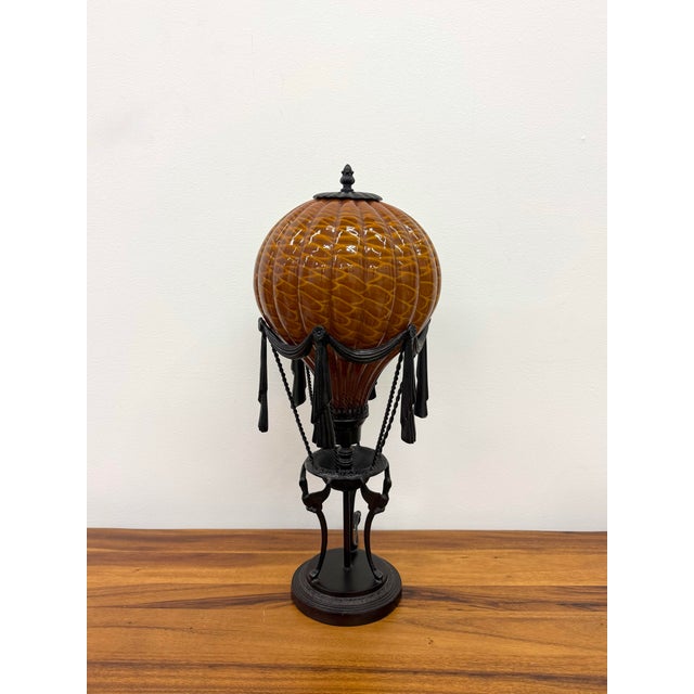 An exceptional Maitland-Smith table lamp modeled after a vintage hot air balloon, featuring a richly textured amber art...