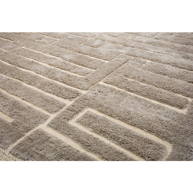 Elegant Moroccan hand-knotted wool rug in Simply Taupe, adorned with a maze-like geometric pattern in Ivory. The subtle...