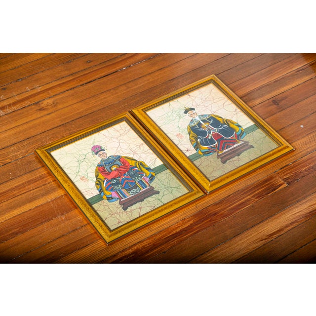 A striking matched pair of vintage Chinese portraits depicting a seated male and female figure in elaborate Qing-style...