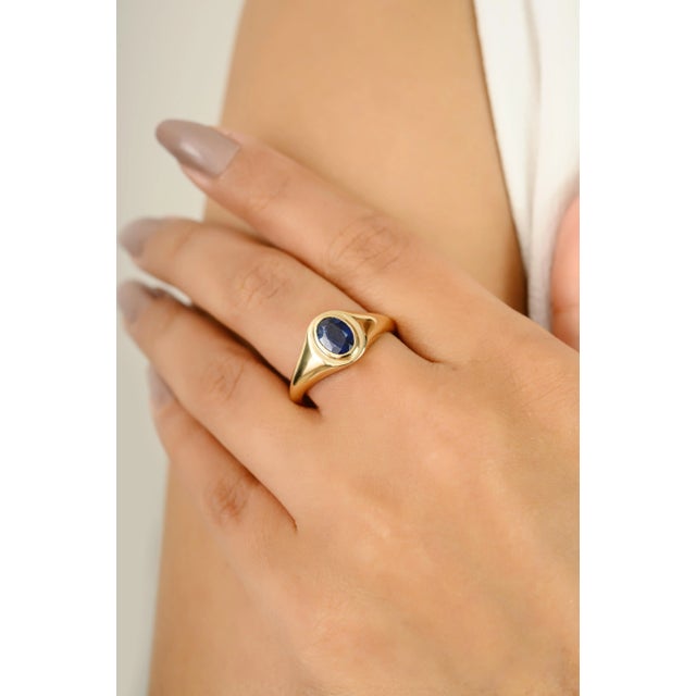 A timeless design featuring a deep blue natural sapphire in an elegant oval cut, bezel set in a sleek 14k gold band. This...