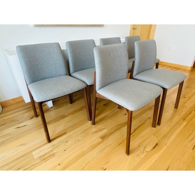Walnut framed dining chairs upholstered in a light gray ducale wool from the Homstvedt & Takagi designed Contour...