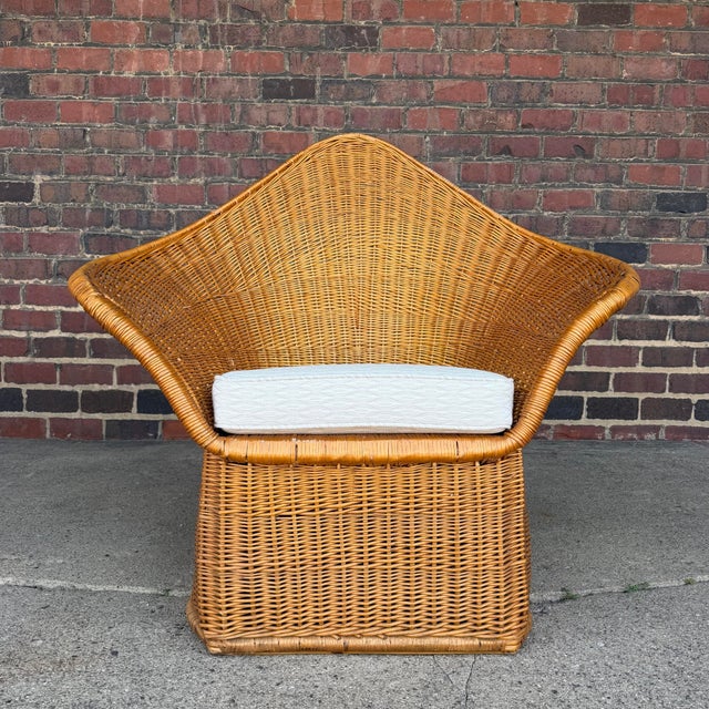 A sculptural woven rattan lounge chair by McGuire, circa 1970s. This piece features a dramatic high-back silhouette with a...