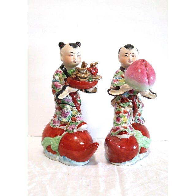This is a pair of vintage Chinese porcelain statues of boys carrying offerings are post-1940..They are so charming. The...