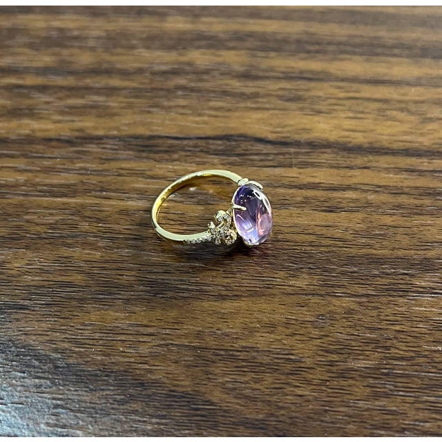 A study in elegance, color, and brilliance. This striking statement ring features a captivating pink cabochon-cut...