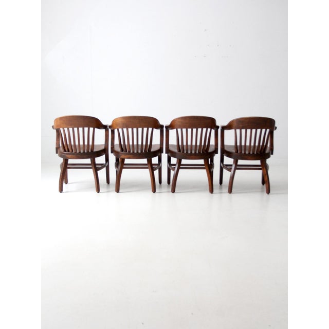 This set of four antique bankers chairs dates to the early 20th century and was originally used in a library. Commonly...