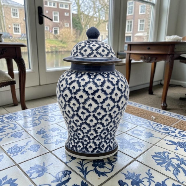 A blue and white porcelain ginger jar with fitted lid, featuring a repeating floral lattice pattern rendered in deep...