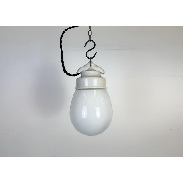 Vintage industrial light made in former Czechoslovakia during the 1970s. It features a white porcelain top and a glass...