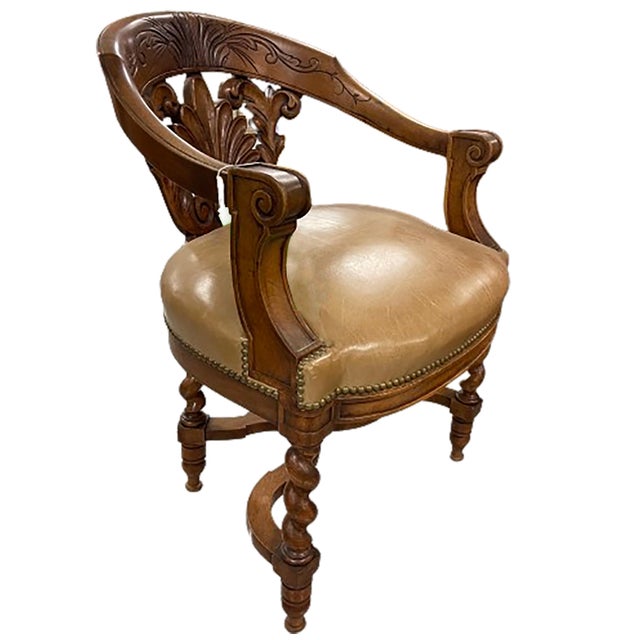 A handsome antique English club chair with hand carved wood features and a light brown leather cushion. The lower pack...