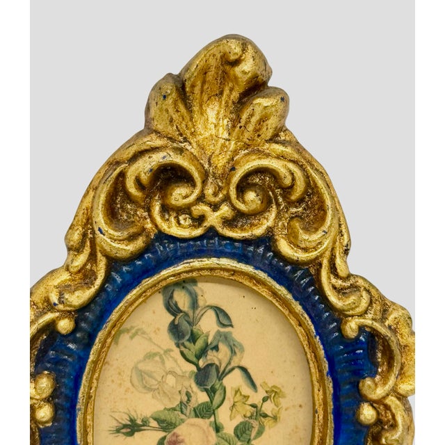 Mid‑20th Century European ornate Rococo‑style wood oval frame in royal blue with worn antique gilt highlights surrounding...