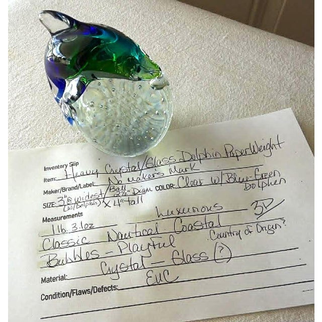 Artisan glass dolphin paperweight showcases a playful nautical design with a vibrant blue and green dolphin perched atop a...