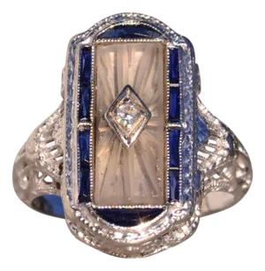 1910s The 186th Avenue: Camphor Glass and Baguette Cut Sapphire Filigree Ring in White Gold, Size 3