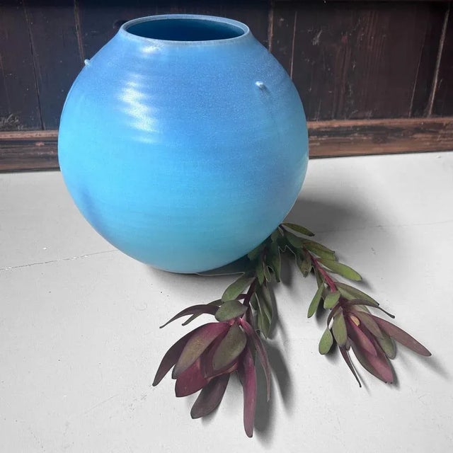 A highly decorative, round ikebana vase finished in a serene sky-blue kōchi glaze, with a subtle transition from light to...