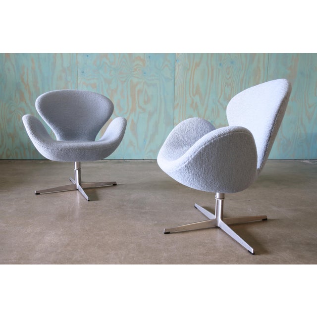 A pair of Swan Chairs designed by Arne Jacobsen for Fritz Hansen newly upholstered in a baby blue nubby boucle fabric....