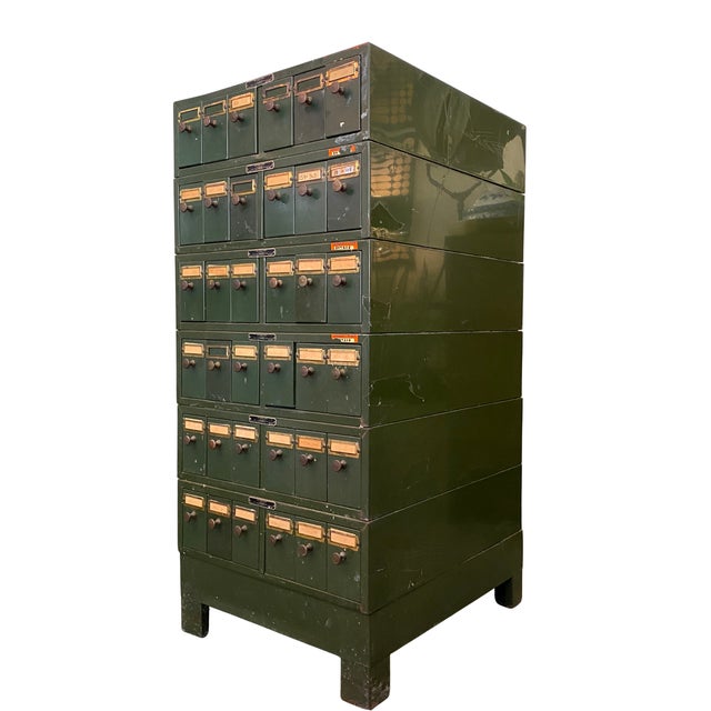 Vintage green metal card catalog cabinet from the University of Illinois, with multiple drawers, brass pulls, and numbered...