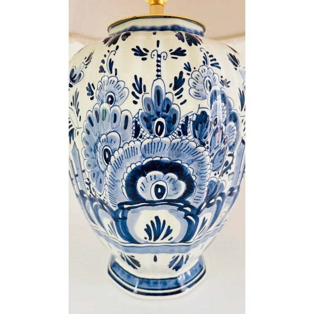 A 20th century delft table lamp, decorated on an off white ground with hand painted flowers and leaves in different tones...