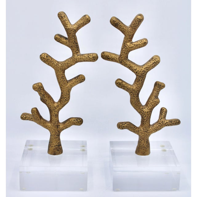 A superb pair of Coastal Mid Century Modern Style Golden Coral Bookends composed of metal on lucite bases. This is a...