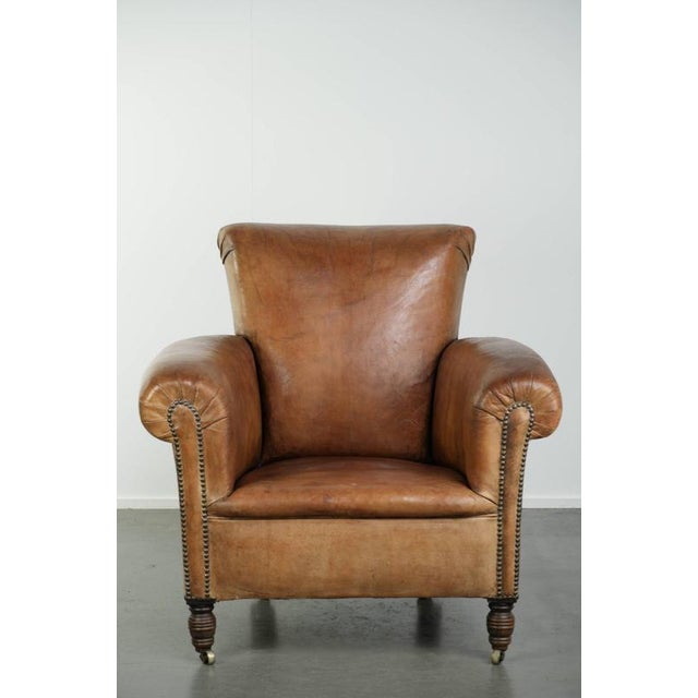 This unique antique sheepskin armchair is crafted in the English style and features a beautiful patina. The armchair has a...
