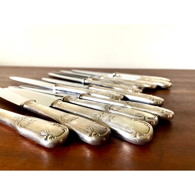 Set of 12 knives from the 1960s, stainless steel blades, silver-plated metal handles with floral and plant motifs. Sold in...