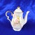 This is a hand painted and signed white teapot with a pink floral design with greenery. The teapot is trimmed in gold and...