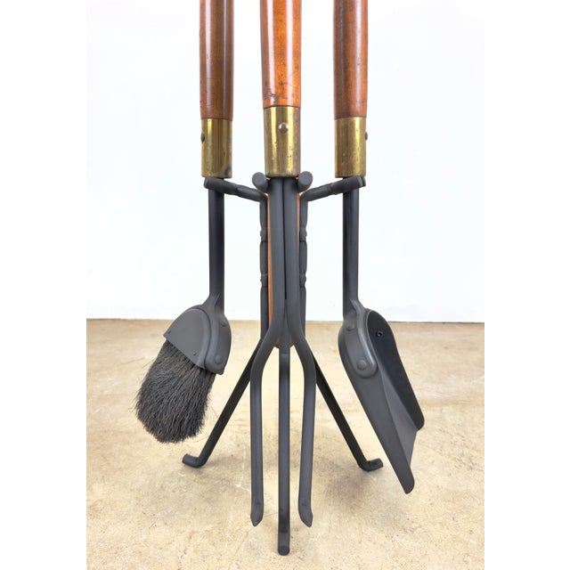 A lovely four-piece mid century modern wrought iron, walnut and brass finish fireplace tool set made by Seymour...