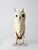 A vintage handmade metal owl sculpture featuring layered cut-metal featherwork, oversized dark eyes, and an aged painted...