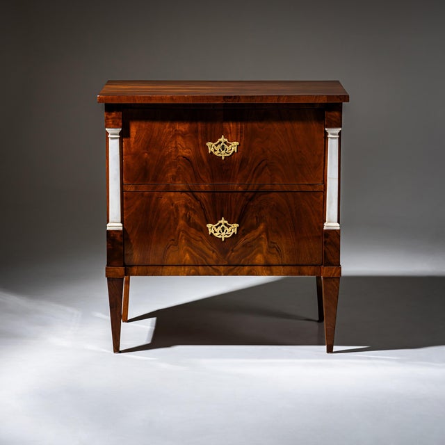Early Biedermeier chest of drawers with two drawers and flanking marble pilasters. The chest rests on tapered square legs...