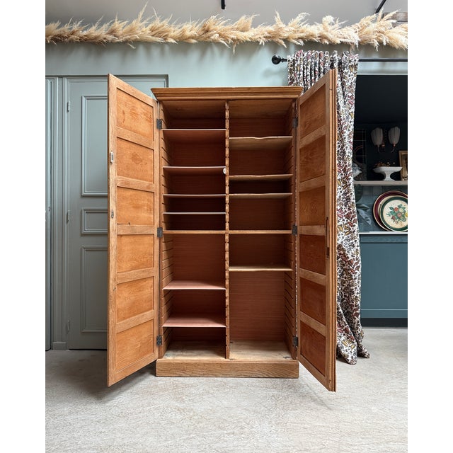 This antique notary's cabinet, crafted from solid oak, impresses with its elegant facade featuring numerous molded panels...