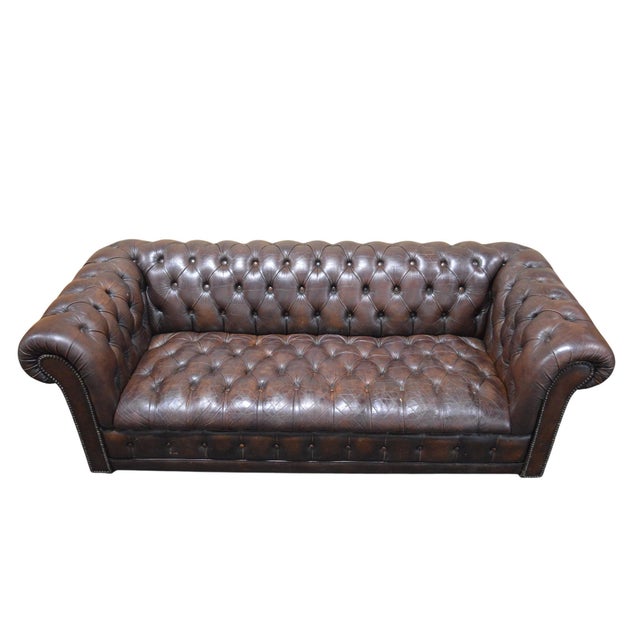 A good, vintage, tufted leather chesterfield sofa. Traditional rolled arm design with studded brass tacking accents. A...