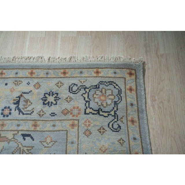 A 10' x 14' hand-knotted wool rug with a pale blue Oushak field of soft palmettes and vines, with navy and apricot accents...