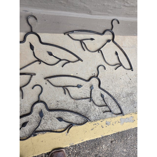 Set of five very unusual hand wrought iron hangers with vinegar and leaf decoration.