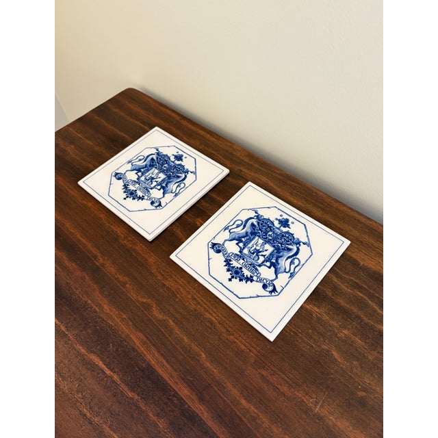 A classic pair of Dutch Delft-style hand painted blue and white porcelain tiles featuring an intricately rendered heraldic...