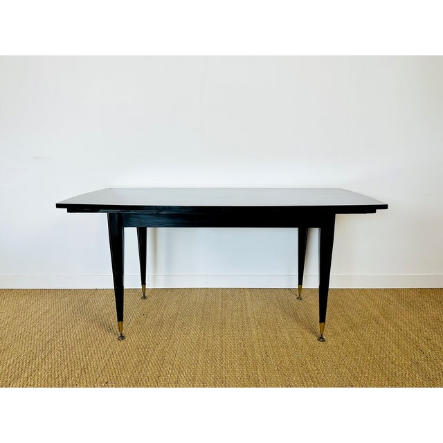 An elegant rectangular dining table dating from the 1940s-1950s, featuring a stunning Macassar veneer top with a rich,...