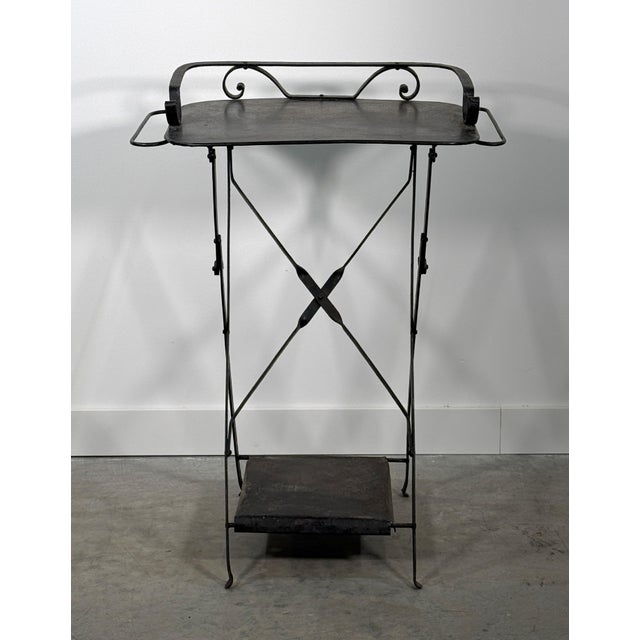 This early 20th century French folding steel table has the right bones for the form: an X-base frame, a tray top with...