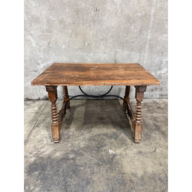 19th century Spanish walnut center table featuring beautifully turned legs and an ornate wrought iron stretcher support....