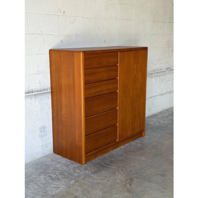 This tall storage unit features an asymmetric profile with a streamlined exterior and a sturdy plinth base. The functional...