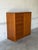 This tall storage unit features an asymmetric profile with a streamlined exterior and a sturdy plinth base. The functional...