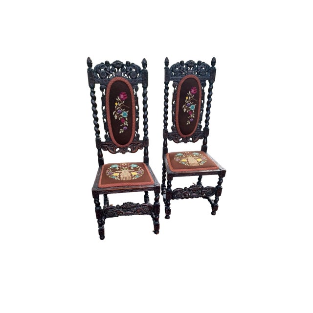 Pair of Vintage Jacobean wooden carved and embroidered side chairs. The intricately carved chairs depict cherubs on the...