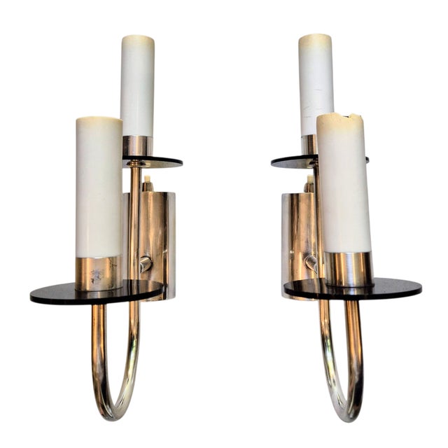 A pair of silver-plated Art Deco-style wall lights. The wall lights are characterised by a simple, geometric design. The...