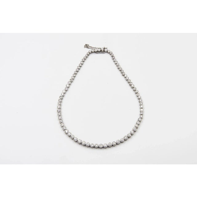 Graduated natural diamond tennis necklace mounted in 14k white gold. There are 80 bezel set diamonds. It has an...