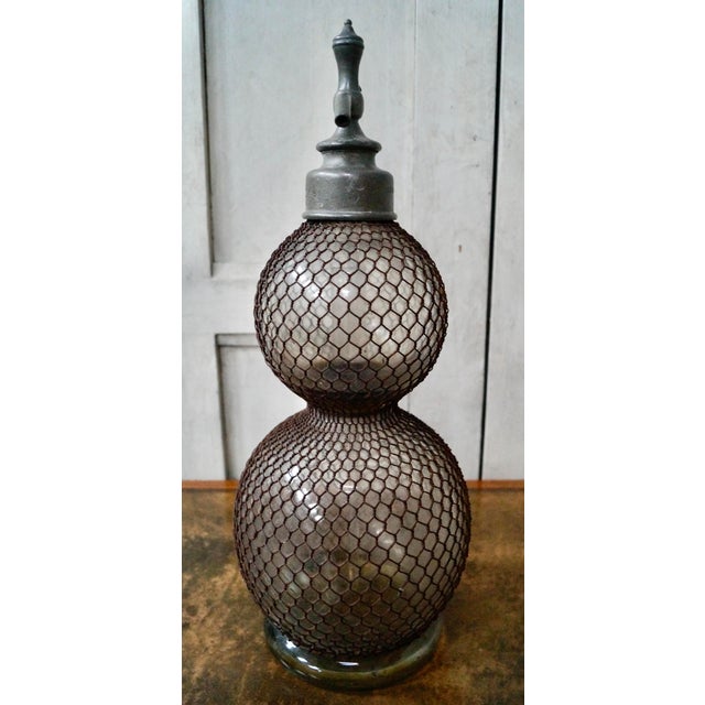 A superb and rare, early Double Gourd soda syphon. Made from hand blown glass surrounded by a protective wire mesh, the...