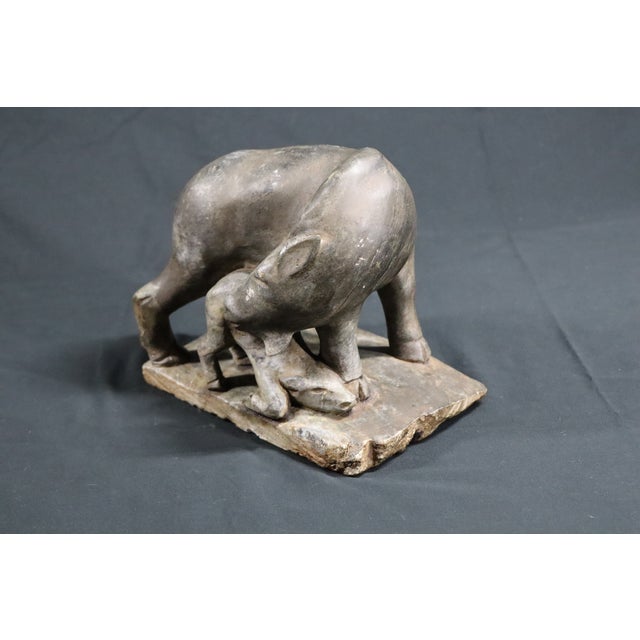 A powerful and tender hand‑carved stone sculpture depicting a mother boar with her baby nestled securely at her side. The...