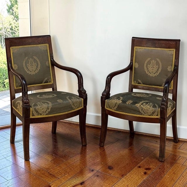 A refined pair of early 19th century French Empire period armchairs, handcrafted in mahogany with the disciplined...