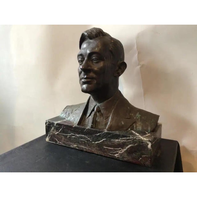 A bronze sculpture portrait bust of former NYC mayor Jimmy Walker sitting on a dark marble base in a suit jacket, collared...