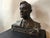 A bronze sculpture portrait bust of former NYC mayor Jimmy Walker sitting on a dark marble base in a suit jacket, collared...