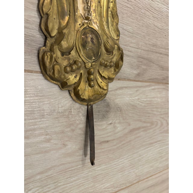 Striking antique French grandfather clock pendulum featuring richly detailed scrolling foliage, floral motifs, and...