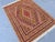 A flatwoven Mushwani kilim featuring an allover diamond lattice in warm gold, burgundy, ivory, and blue, framed by a...
