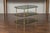 A vintage brass tiered table from the mid-20th century, with glass shelves and foliage motifs. Created during the...