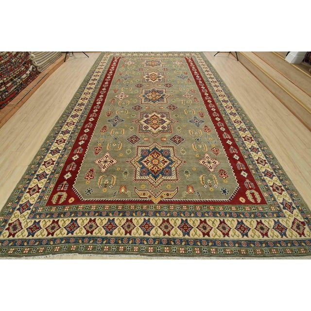 A traditional Caucasian Kazak rug hand-knotted with fine wool on a cotton foundation. This oriental rug features a row of...