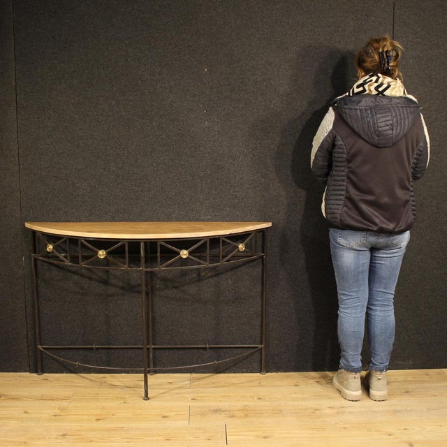 A French half-moon console table from the mid-20th century. A beautifully wrought iron furniture with gilded metal...